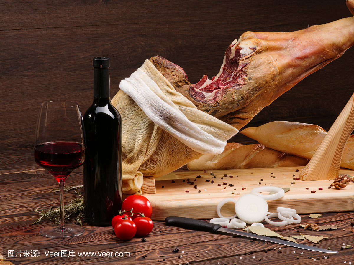 木桌上的西班牙火腿配西红柿,一杯和一瓶红酒.家常菜,餐厅菜,美食.